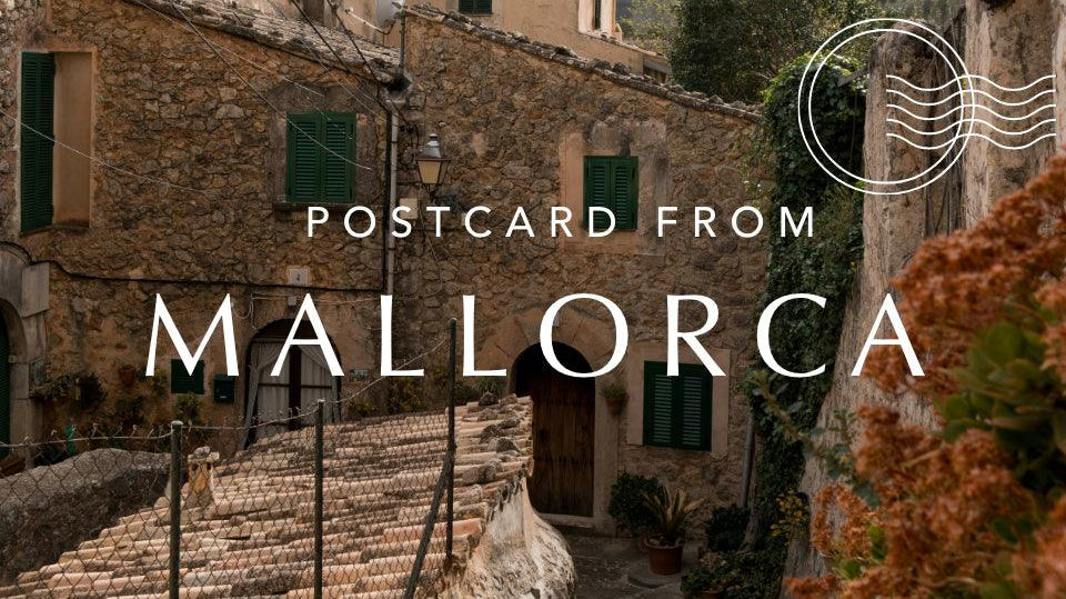 Charming Mallorca stone village alleyway with rustic houses, green shutters, and mountain view