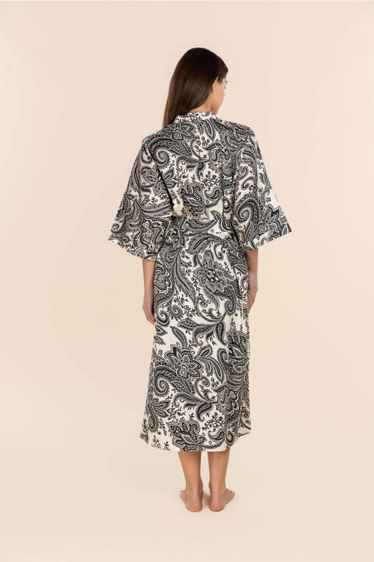 Woman wearing a black and white patterned dress against a beige background