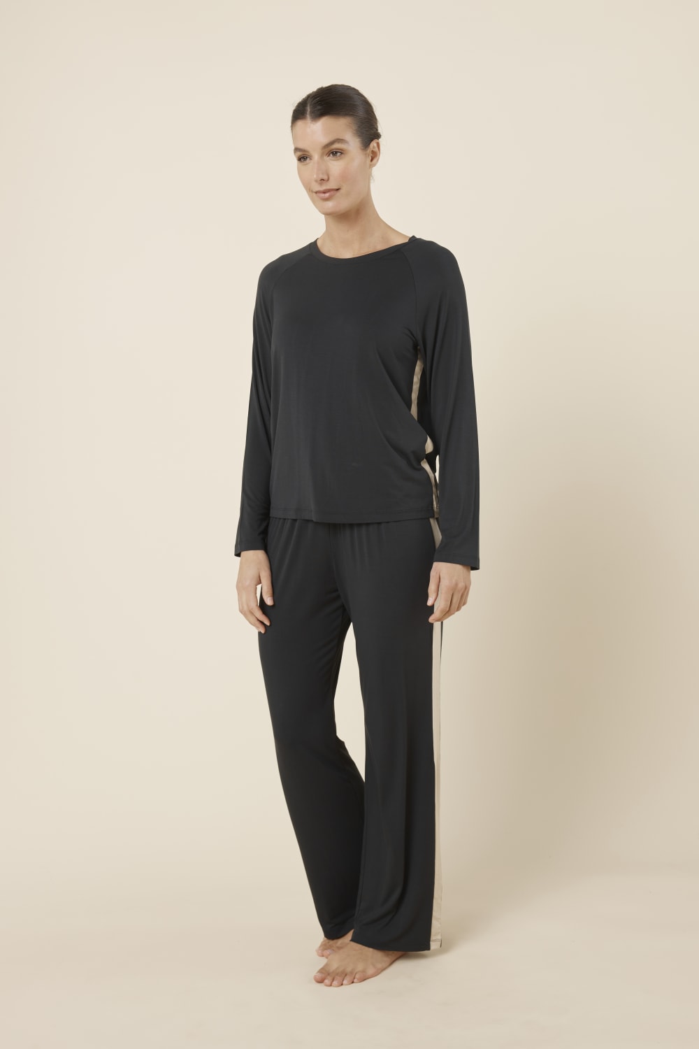Woman wearing Anya Bamboo Sporty PJ Set Black standing facing forward, showing the long sleeve crew neck top and relaxed straight leg bamboo pants.