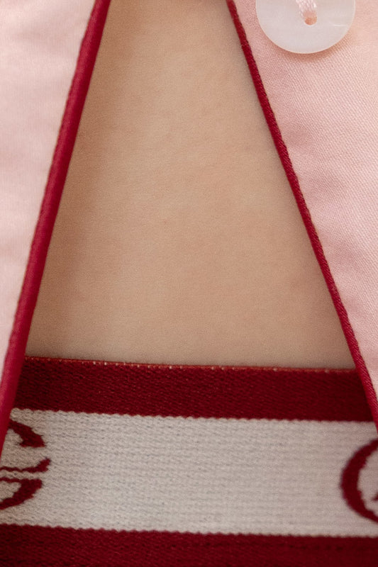 Close-up of a garment with red trim and a button, featuring a patterned fabric.