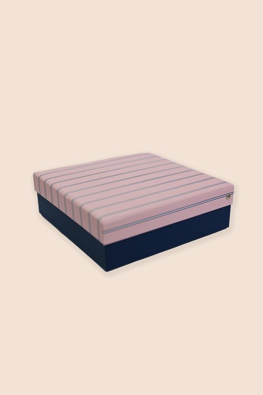 Box spring with pink and blue striped top and navy base on a beige background