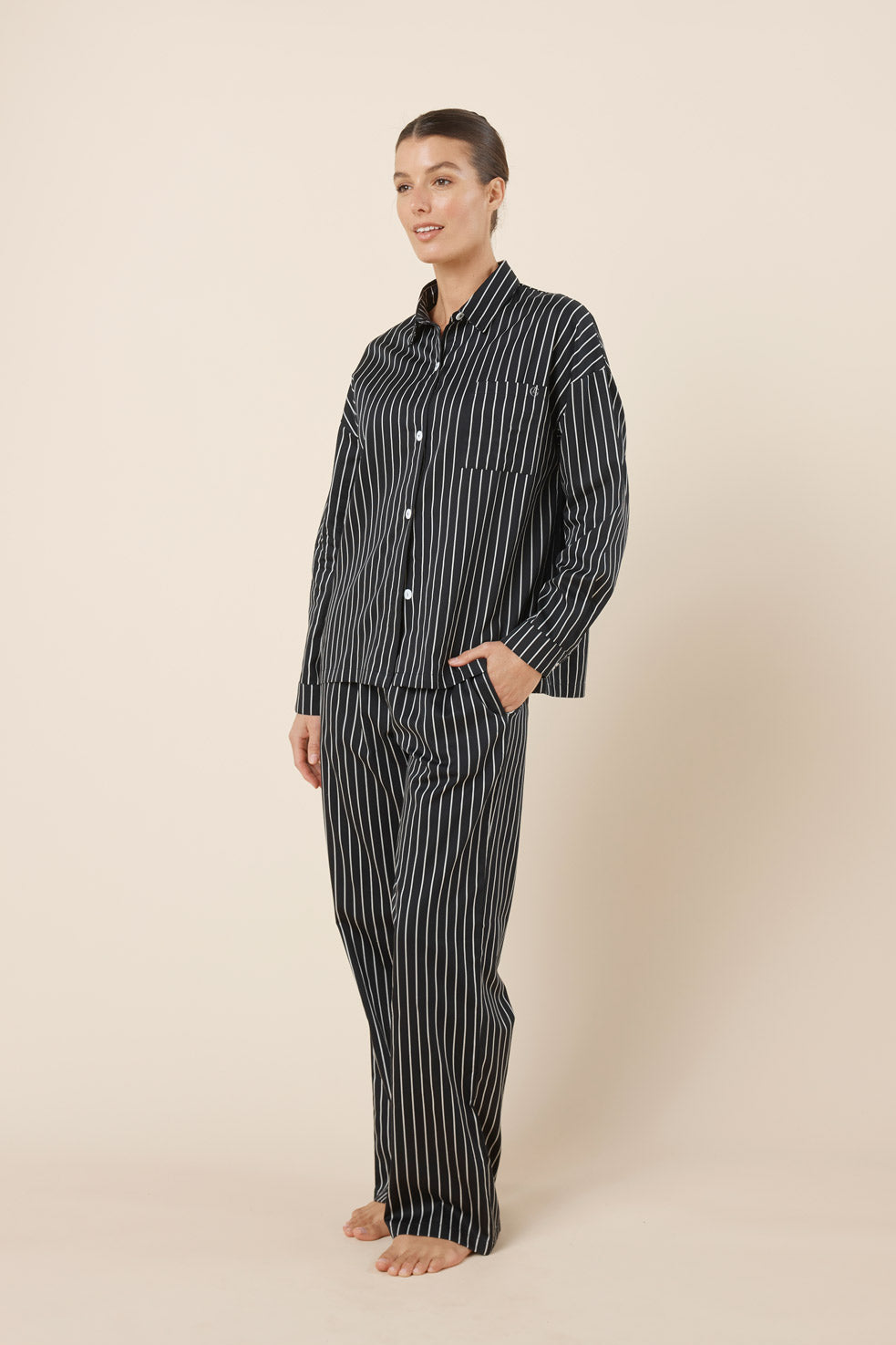 Woman wearing a black and white striped pajama set on a beige background