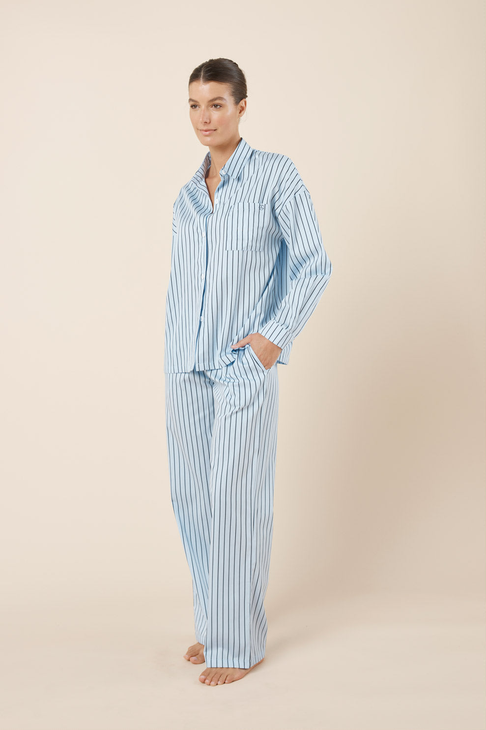 Woman wearing a blue and white striped pajama set on a beige background
