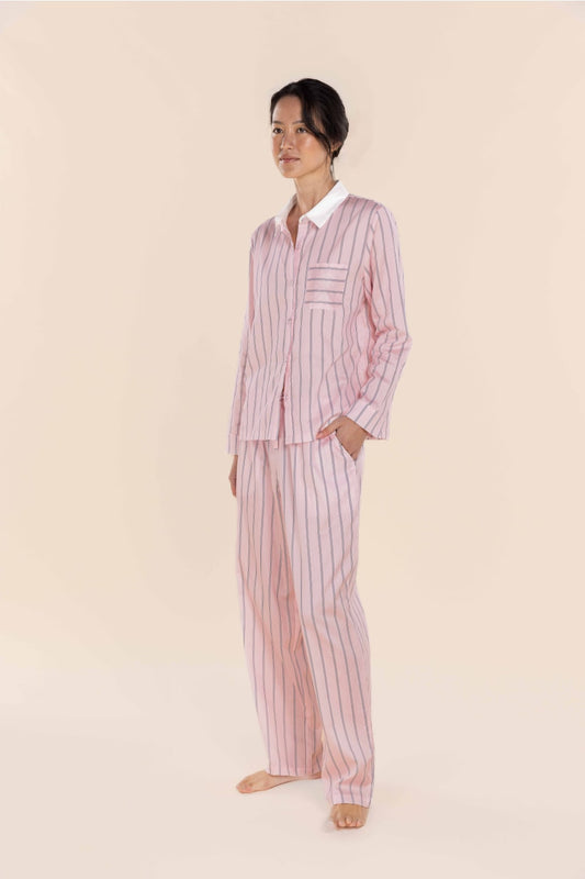 Woman wearing a pink striped pajama set against a beige background