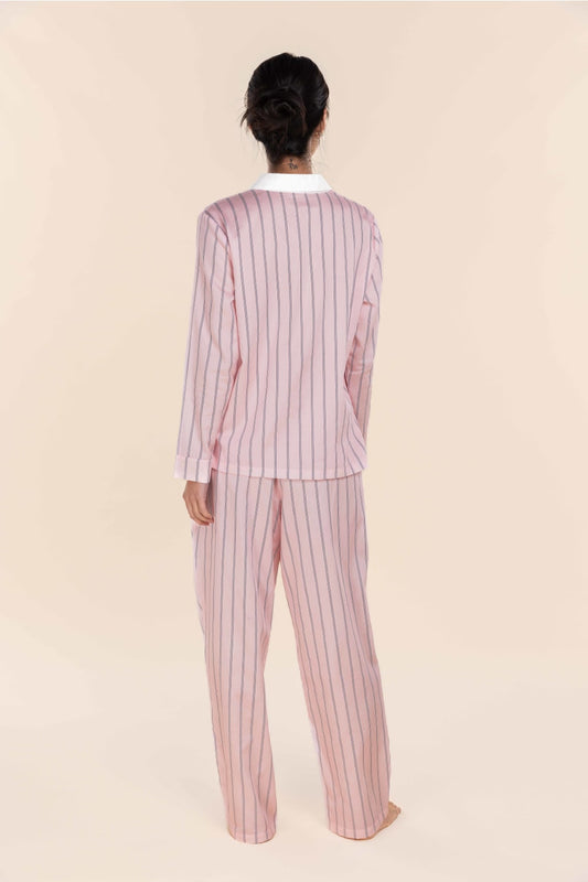 Person wearing a pink and white striped pajama set on a beige background