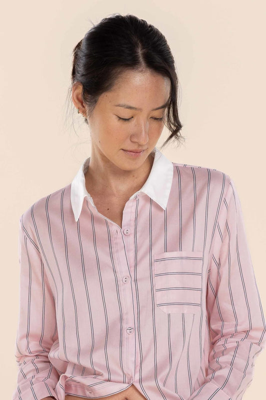 Woman wearing a pink striped shirt against a beige background