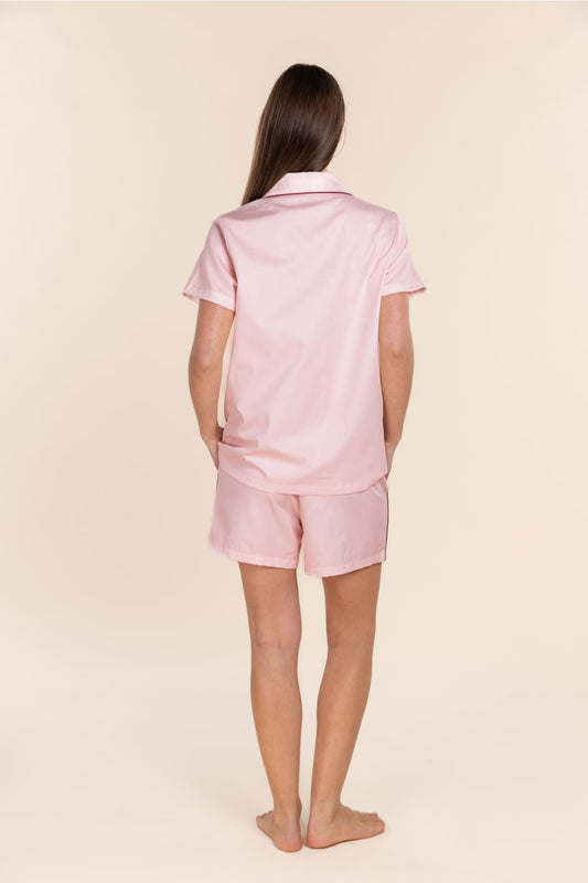 Person wearing a pink pajama set on a beige background