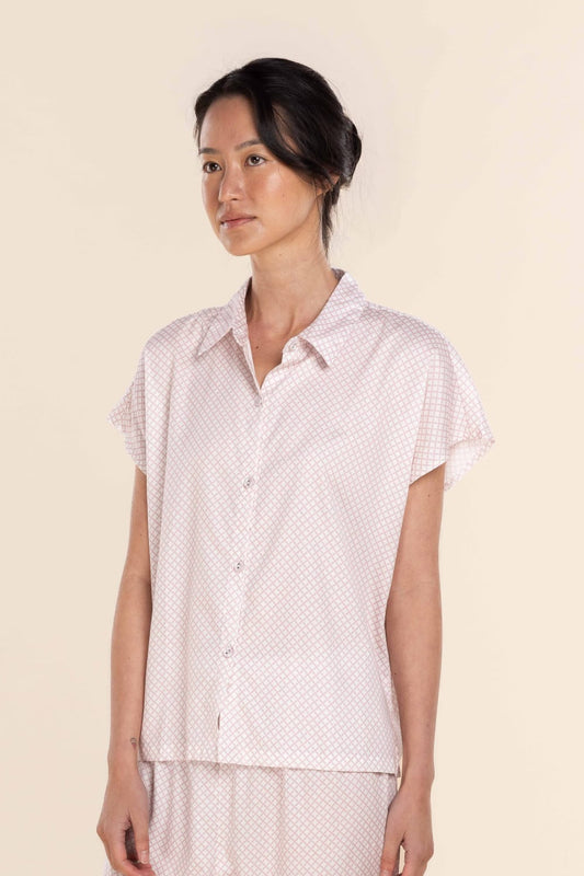 Woman wearing a short-sleeve patterned shirt against a beige background
