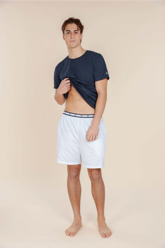 Man wearing a navy t-shirt and white shorts on a beige background