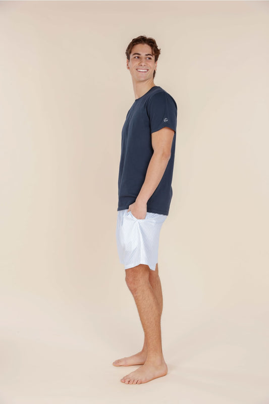 Man wearing a navy t-shirt and white shorts on a beige background