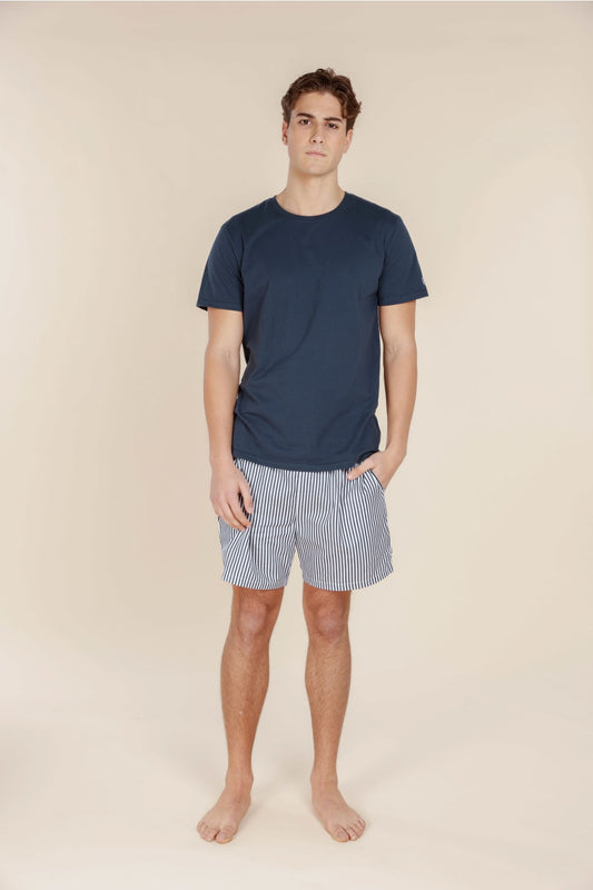 Man wearing a navy t-shirt and striped shorts on a beige background