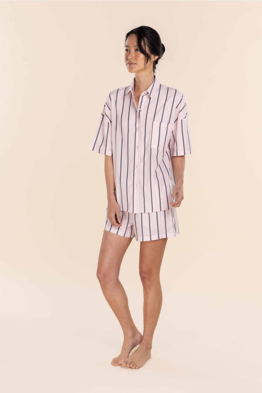 Woman wearing a striped pajama set on a beige background