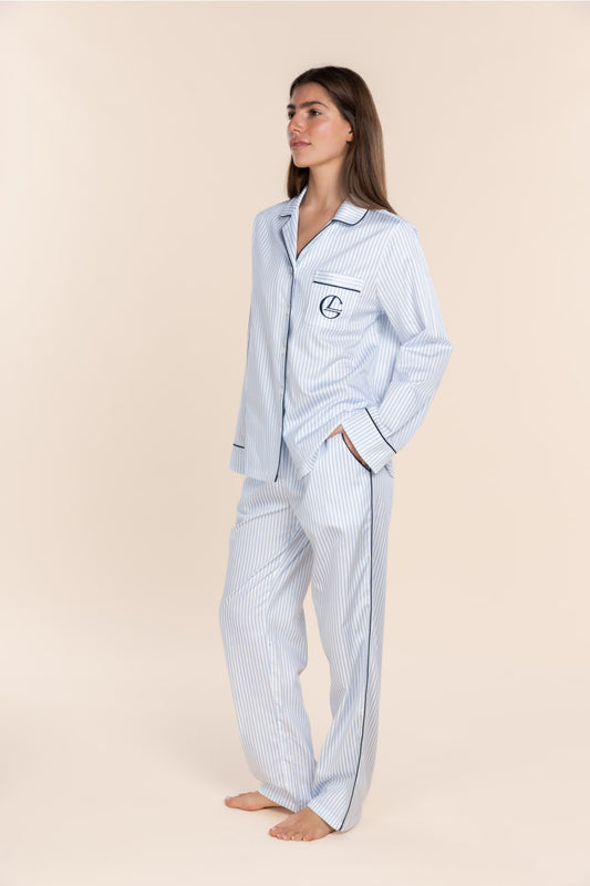 Woman wearing a blue striped pajama set on a beige background