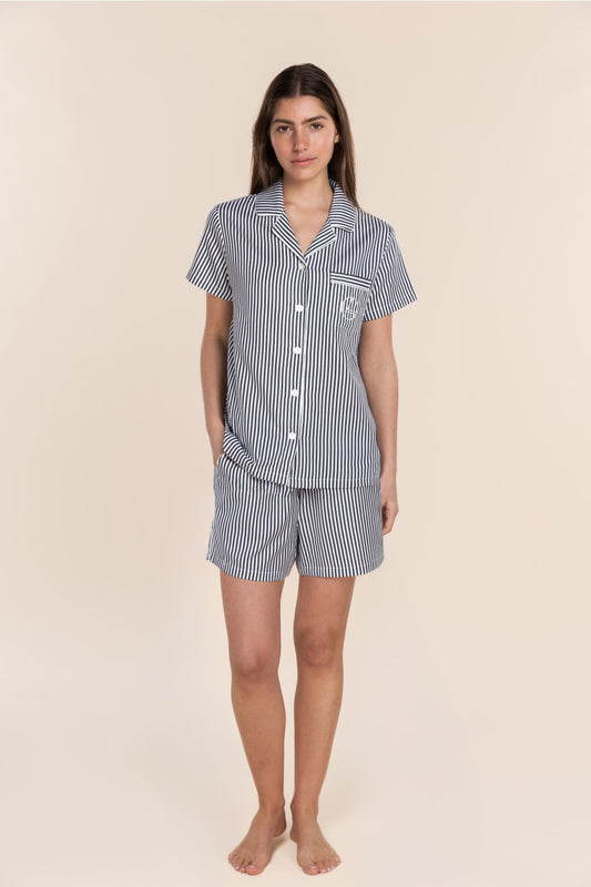 Woman wearing a navy and white striped pyjama set on a beige background