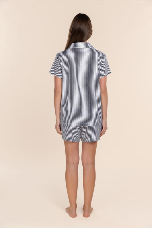 Woman wearing a blue and white striped pyjama set on a beige background