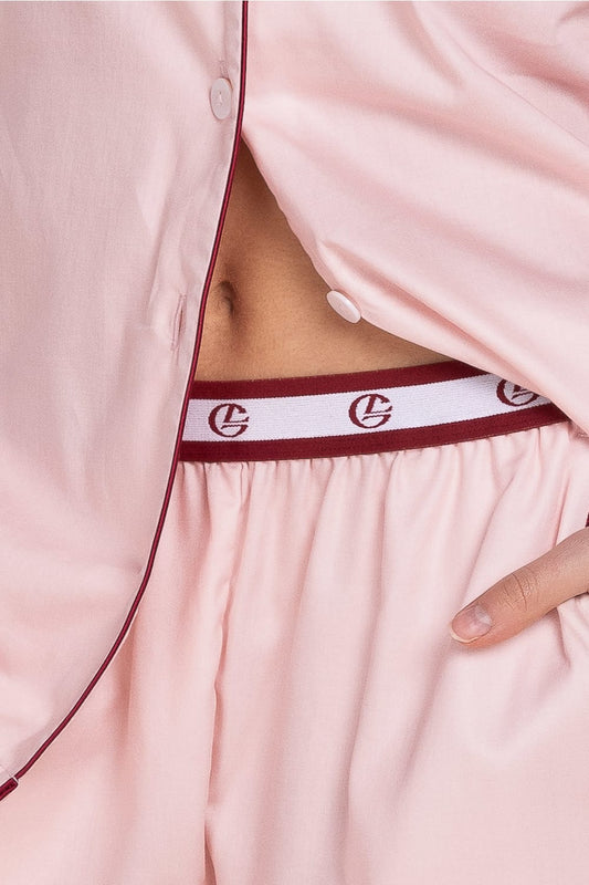 Close-up of a pink satin nightgown with a red waistband featuring a logo.