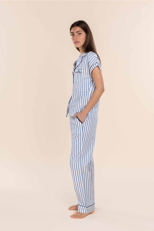 Woman wearing a blue and white striped pajama set on a beige background