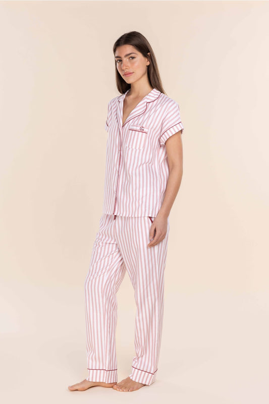 Woman wearing a pink and white striped pajama set against a beige background