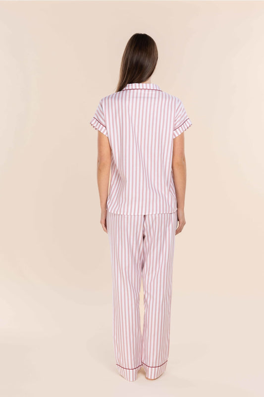 Woman wearing a pink and white striped pajama set on a beige background