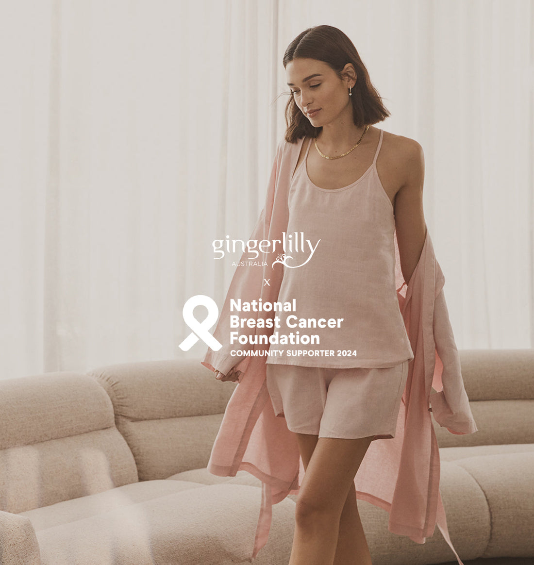 Woman in soft pink Gingerlilly Sleepwear set for breast cancer awareness on beige sofa