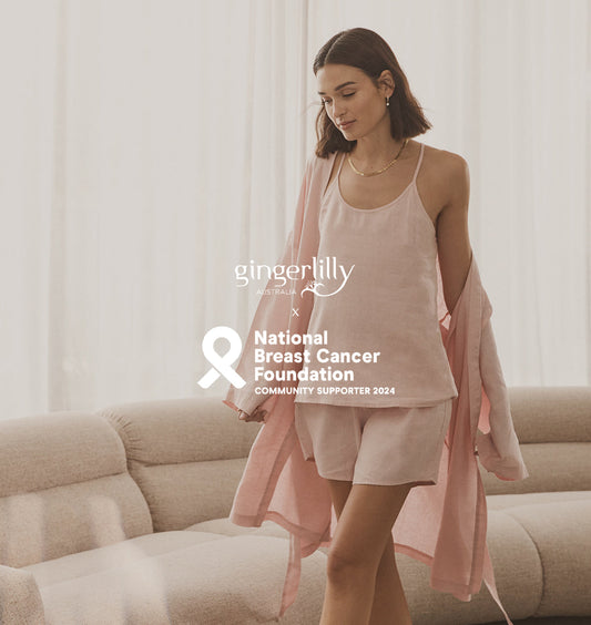 Woman in soft pink Gingerlilly Sleepwear set for breast cancer awareness on beige sofa