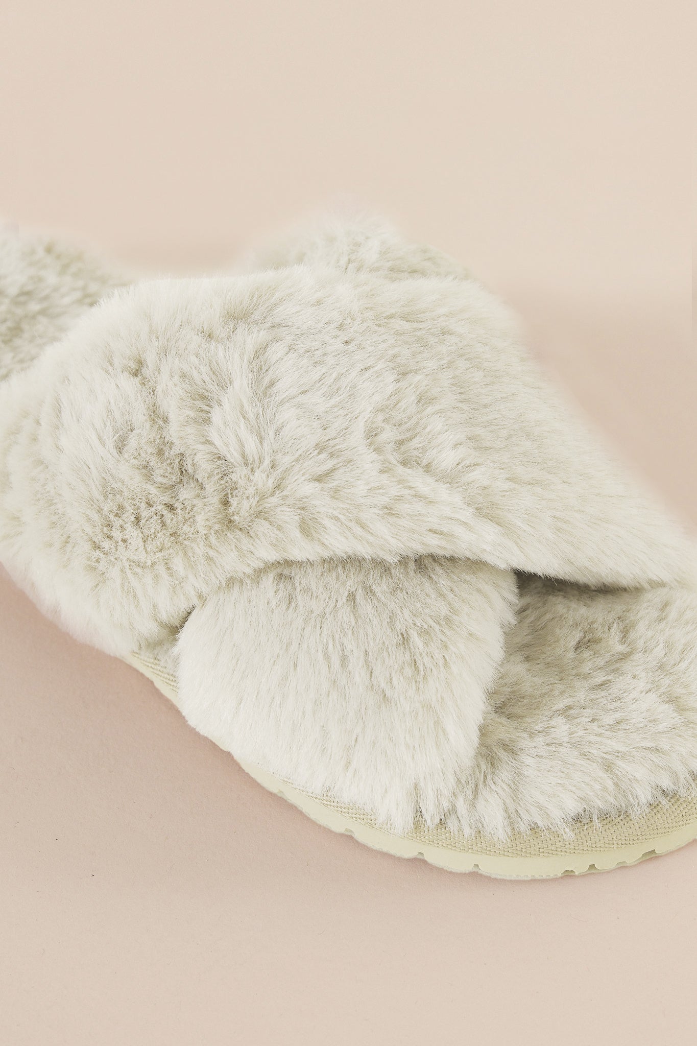 Fluffy white slipper on a beige background