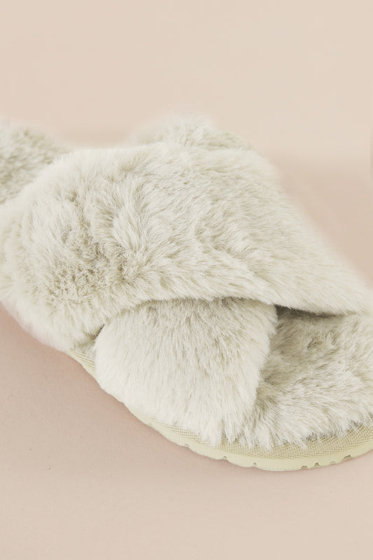 Fluffy white slipper on a beige background