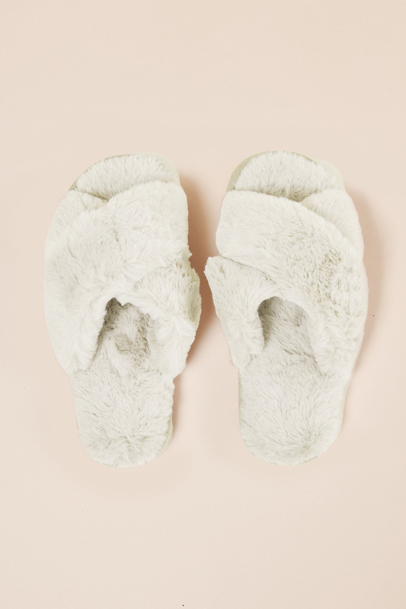 Pair of fluffy green slippers on a beige background
