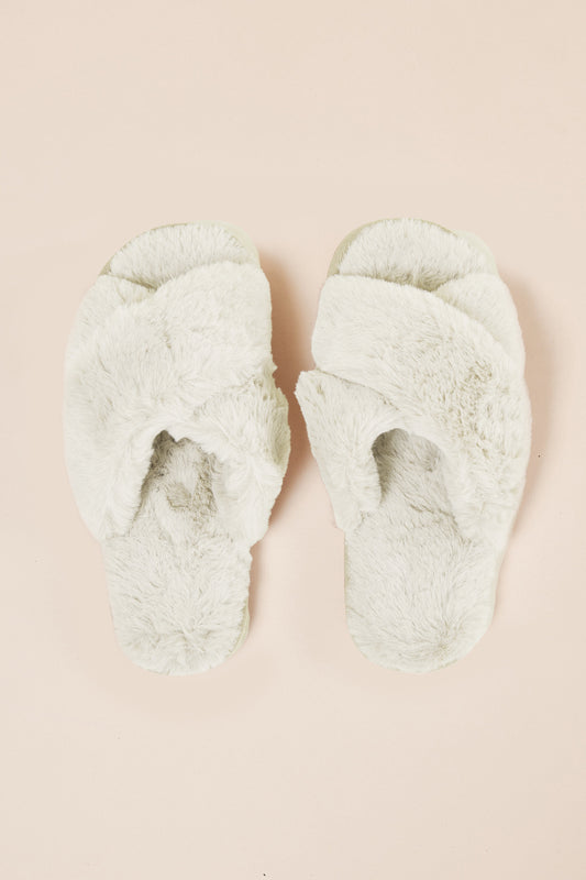 Pair of fluffy green slippers on a beige background