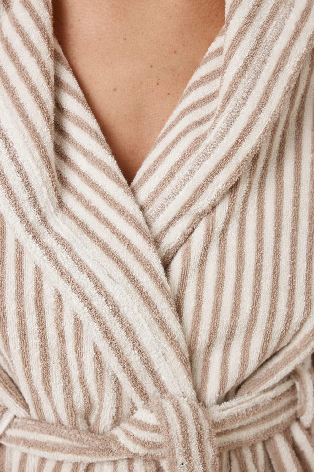 Detail of fabric of woman wearing a striped adriana terry towel robe in biscuit colour showing the robe tie