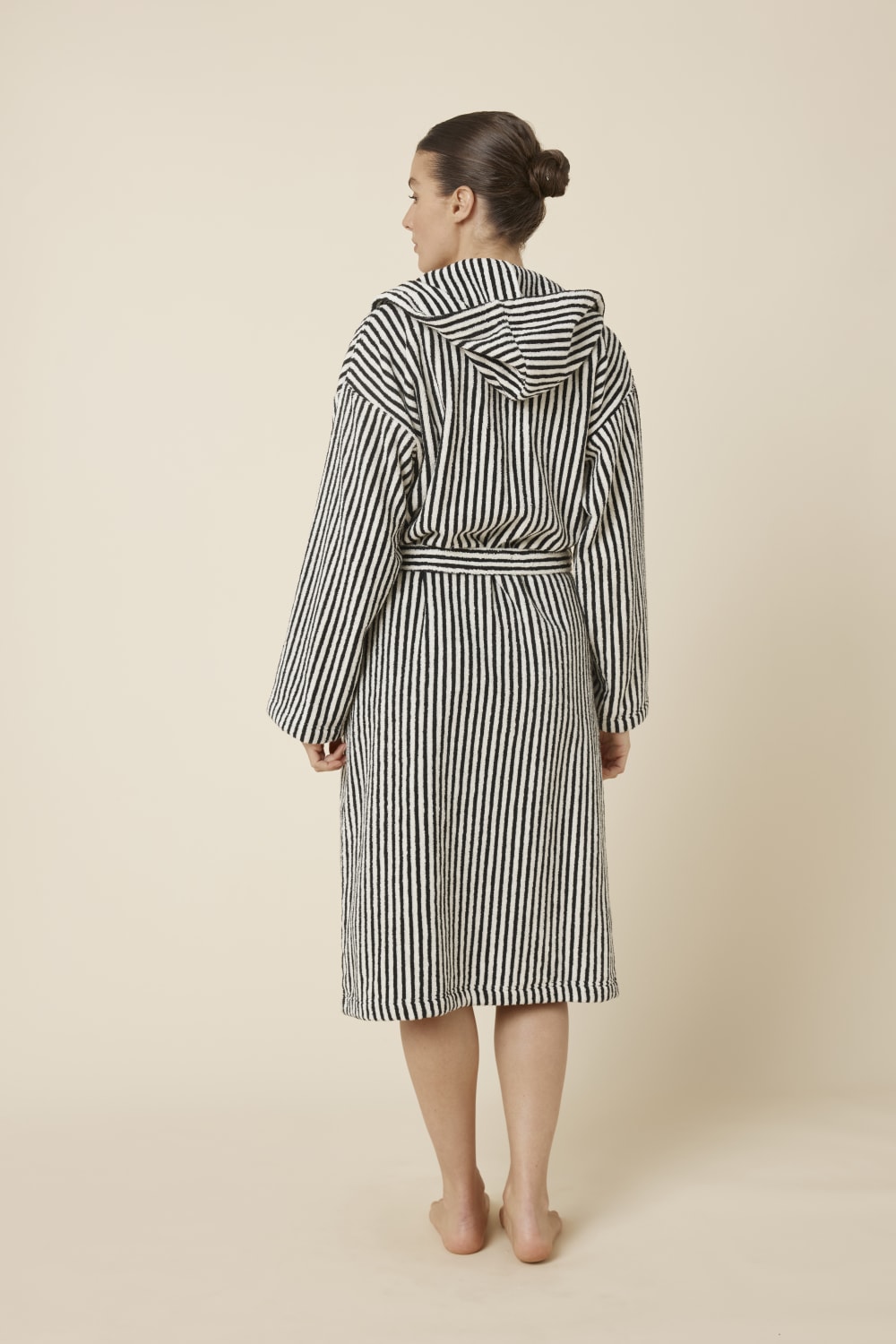 Woman wearing a striped adriana terry towel robe in black colour from back view standing