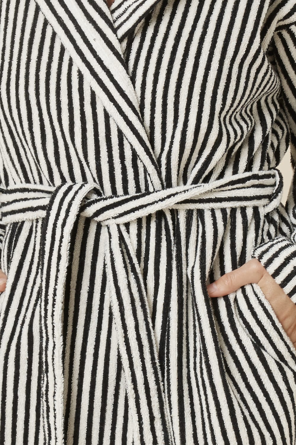 Detail shot of the striped adriana terry towel robe in black colour with waist tie and hands in pockets