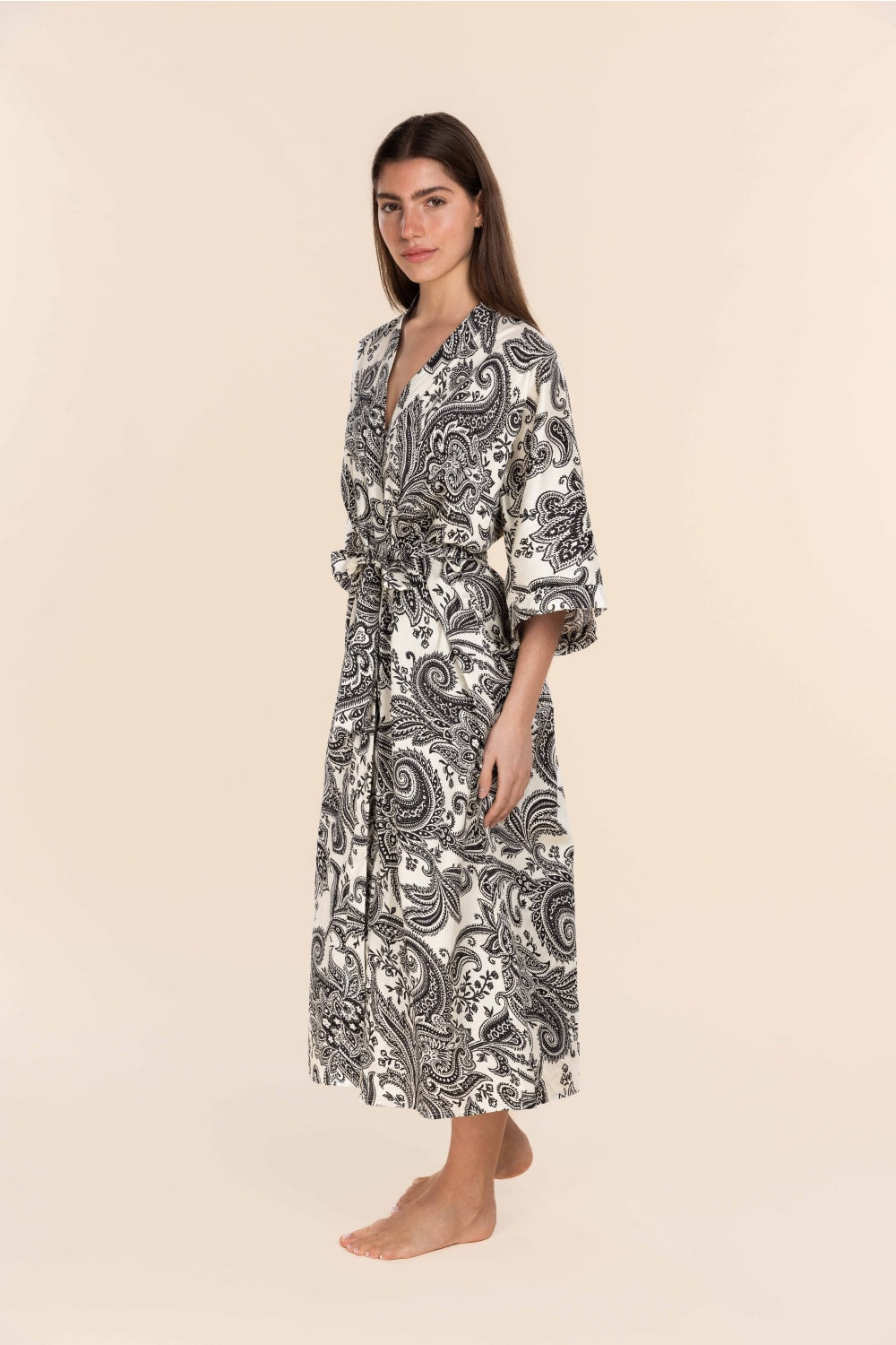 Woman wearing a black and white patterned robe on a beige background