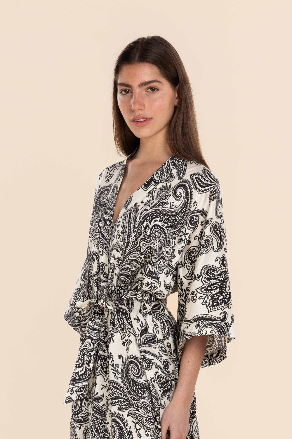 Woman wearing a black and white patterned kimono-style garment on a beige background