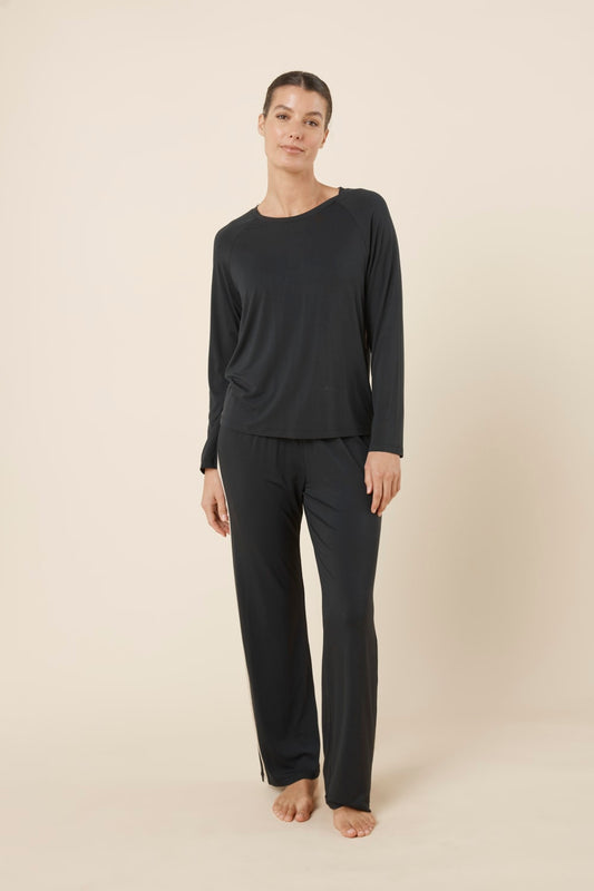 Woman wearing Anya Bamboo Sporty PJ Set Black standing full length, showing the sporty lounge silhouette with crew neck top and relaxed pants.