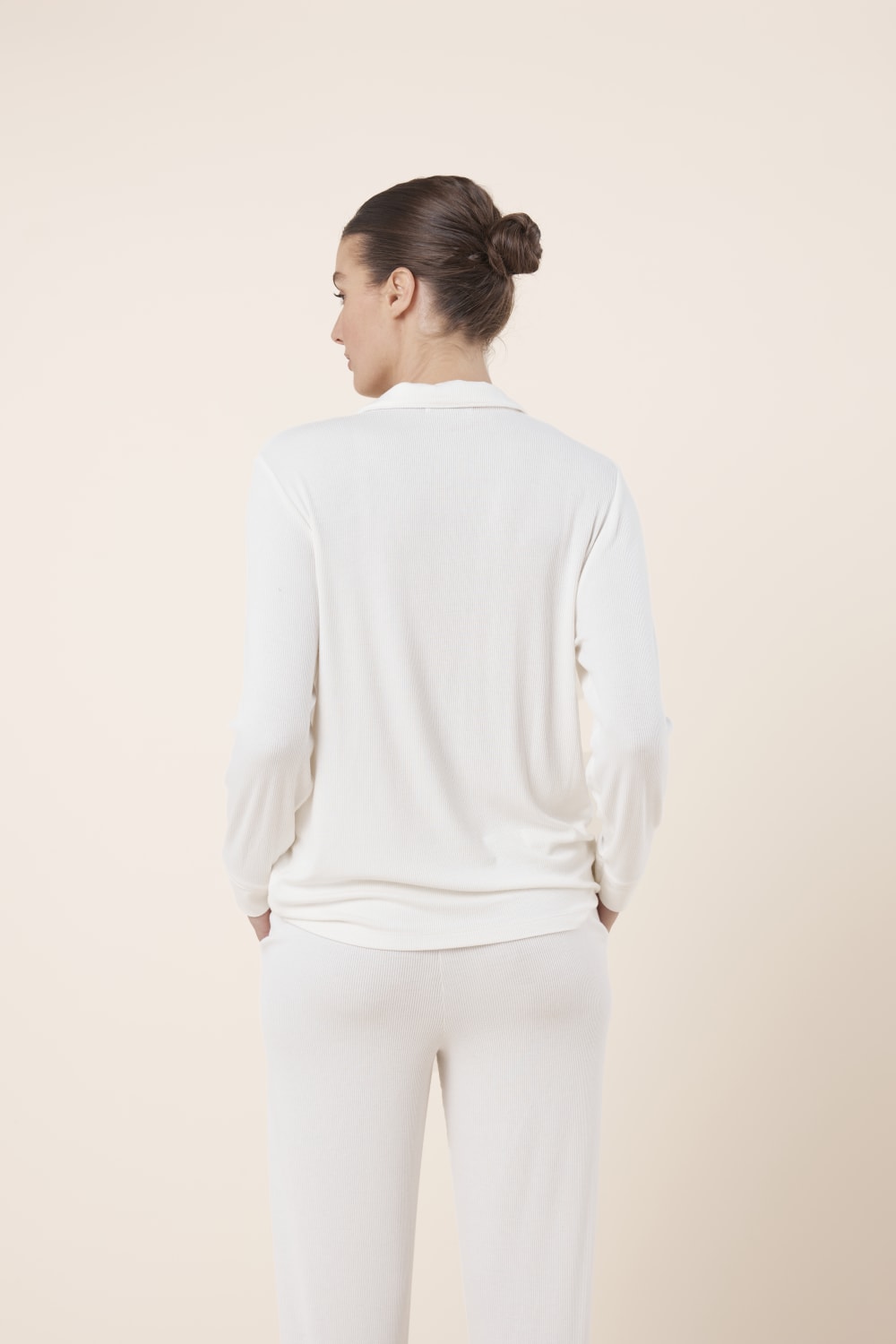 Woman wearing Athens Ribbed Long Pants Ivory, back view styled with coordinating ribbed lounge top