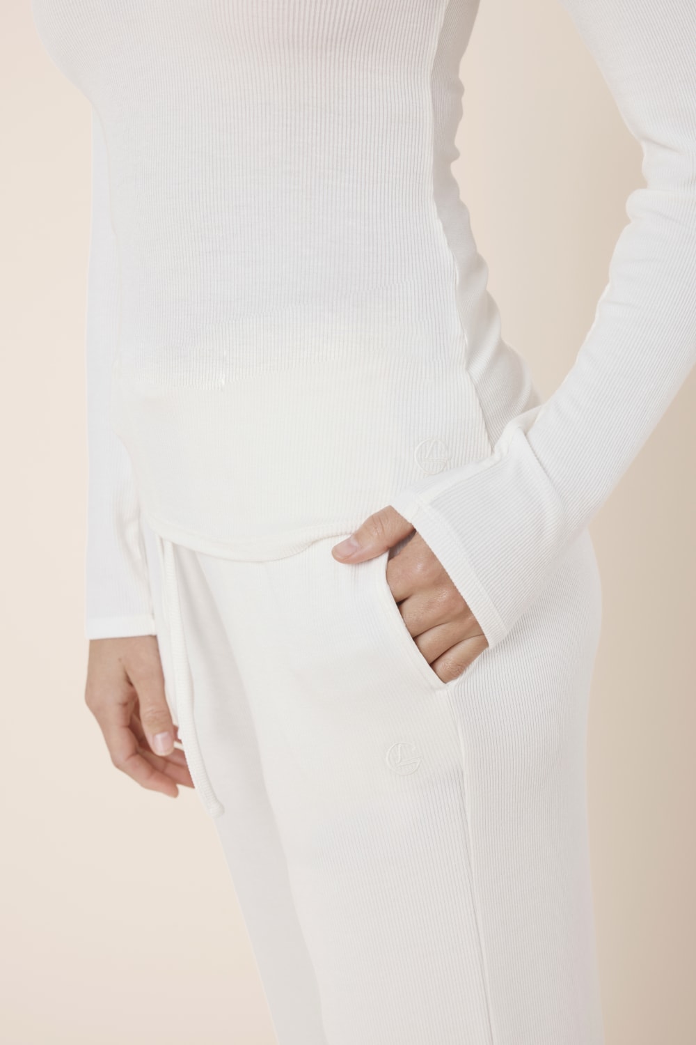 Woman wearing Athens Ribbed Long Pants Ivory, close up of ribbed fabric pocket with Gingerlilly logo detail