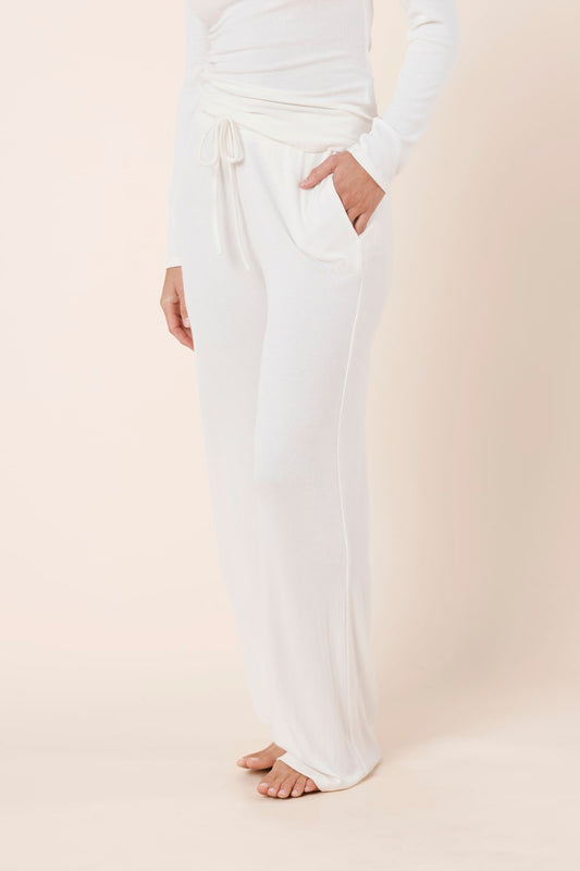 Woman wearing Athens Ribbed Long Pants Ivory, side view showing relaxed wide leg fit and soft ribbed texture