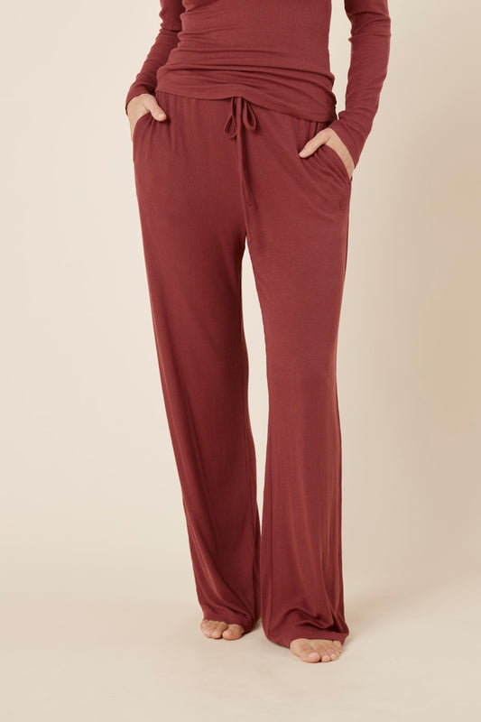 Woman wearing the athens ribbed Long pant burgundy from front view with hands in pockets