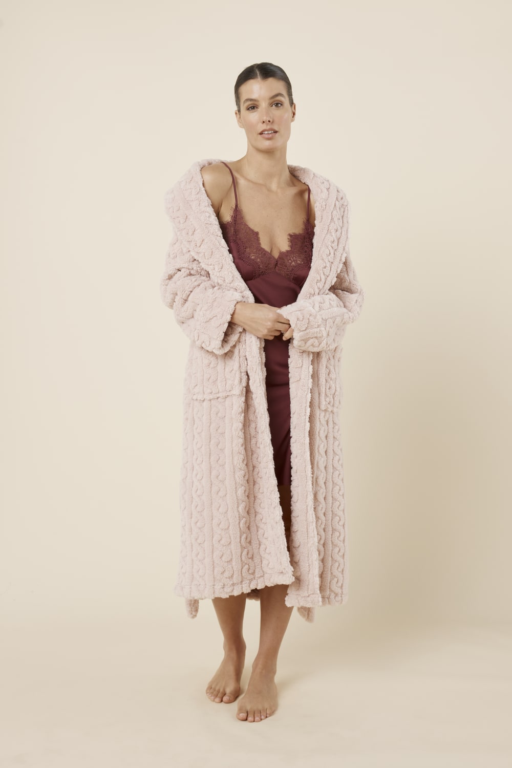 Woman wearing Azalia Silky Satin Short Chemise Burgundy styled with a light robe, showing the satin slip dress with lace trim and delicate straps.