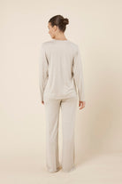 Woman wearing a brianna lounge set oatmeal on a plain beige background back view
