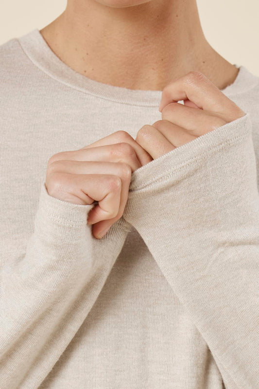 Woman wearing a brianna lounge set oatmeal on a plain beige background close up view of the cuff and neck