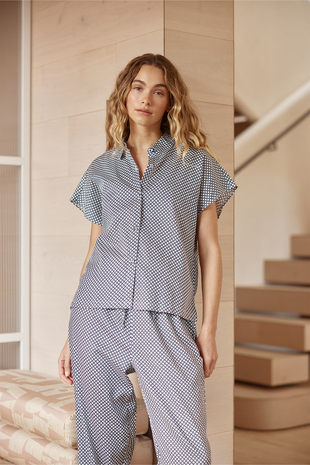 Woman wearing a blue and white checkered outfit standing on a staircase.
