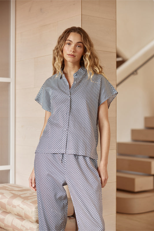 Woman wearing a blue and white checkered outfit standing on a staircase.