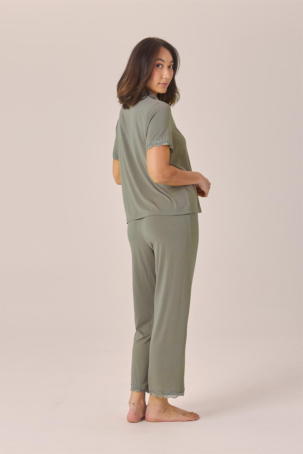 Woman wearing the Dianne Bamboo Long PJ Set with Lace in Olive, side back view showing lace-trimmed pant hems
