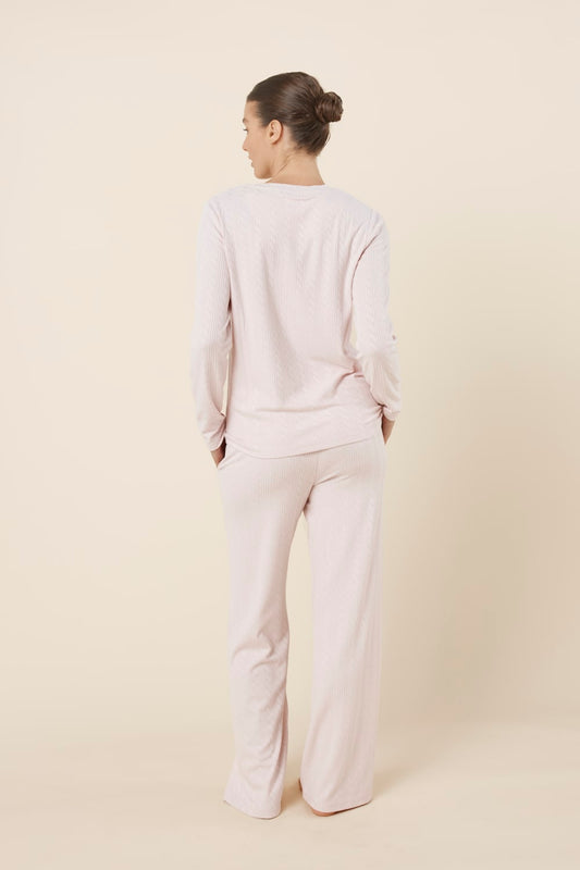 Woman wearing a ellie lightweight velour cable knit set pink long-sleeve top and pants on a beige background back view