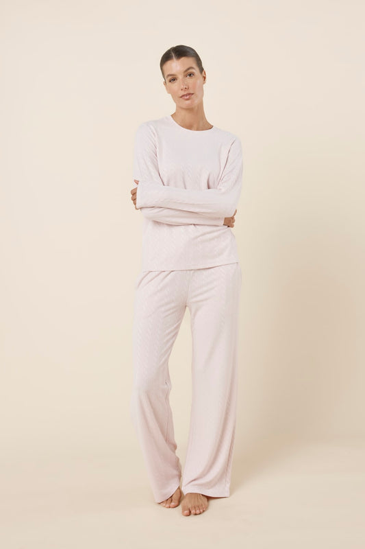 Woman wearing a ellie lightweight velour cable knit set pink long-sleeve top and pants on a beige background front on view with hands crossed
