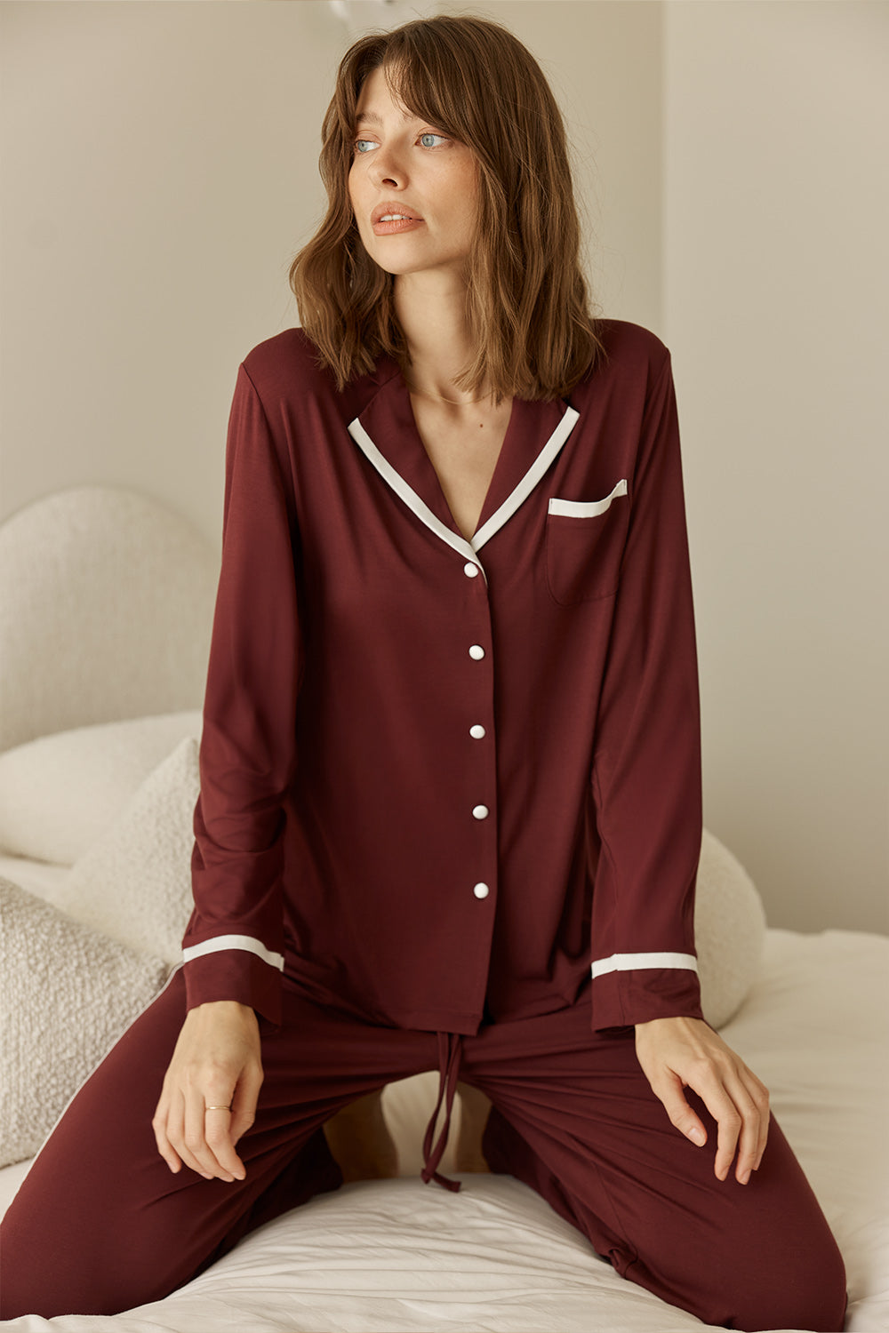 Grace Bamboo PJ Set Burgundy on model sitting, long sleeve bamboo pyjama set with contrast piping and button front detail