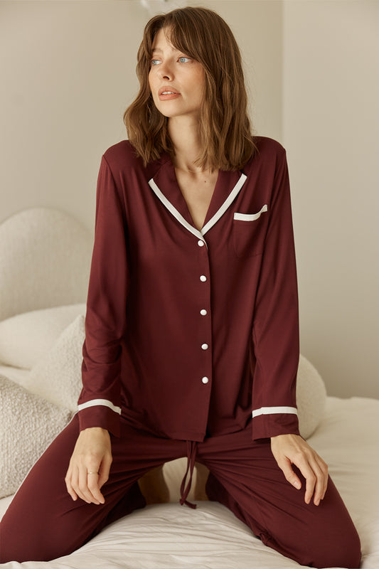 Grace Bamboo PJ Set Burgundy on model sitting, long sleeve bamboo pyjama set with contrast piping and button front detail