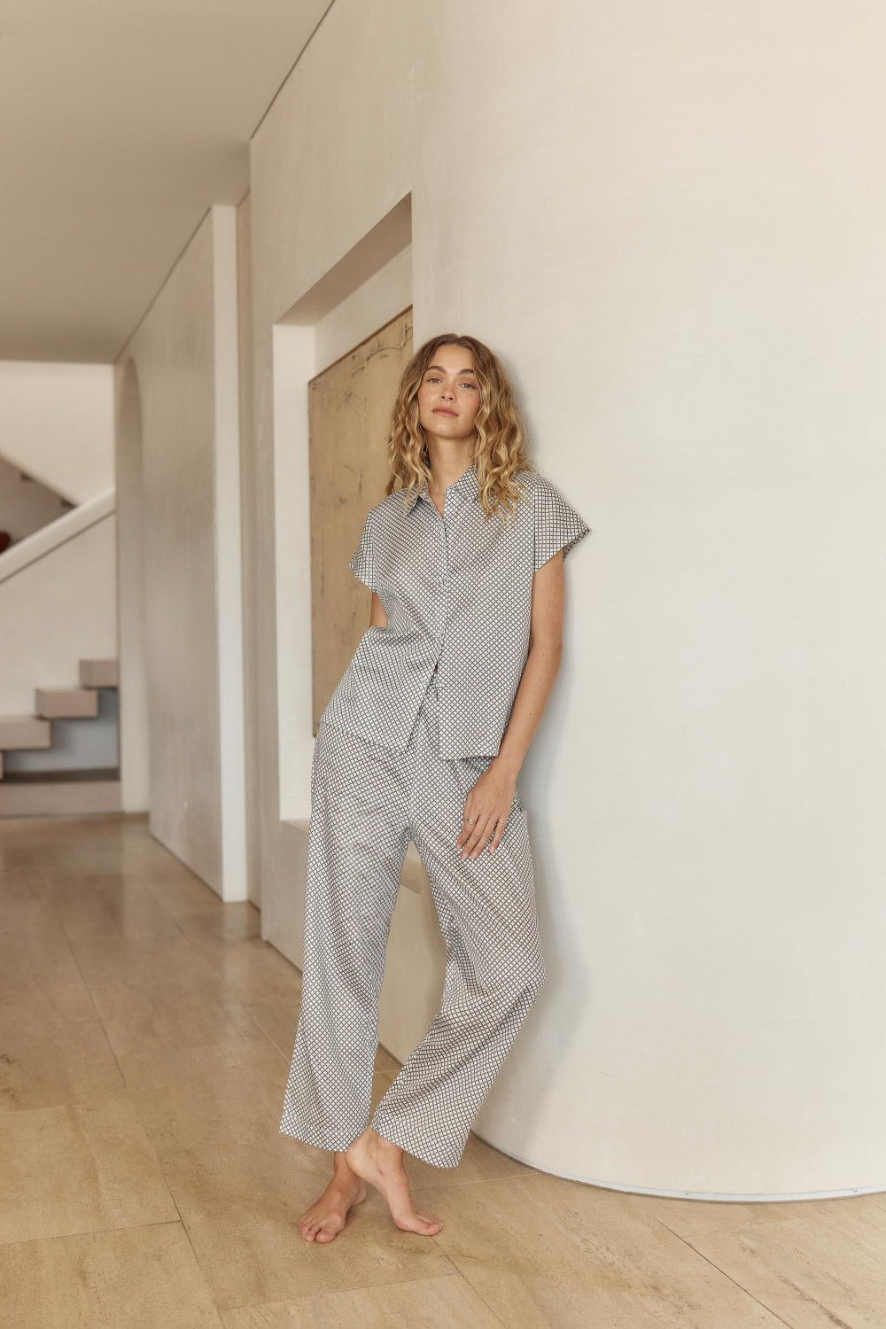 Woman wearing a checkered outfit standing in a modern interior setting.